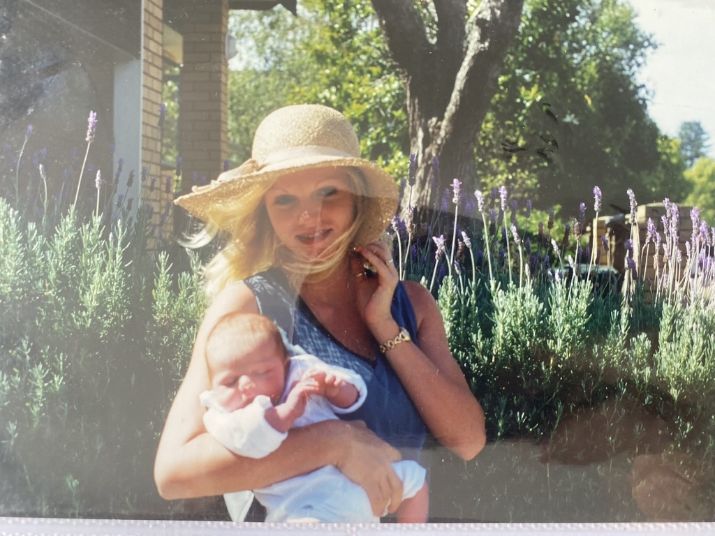 Alysha in a sun hat holding her baby