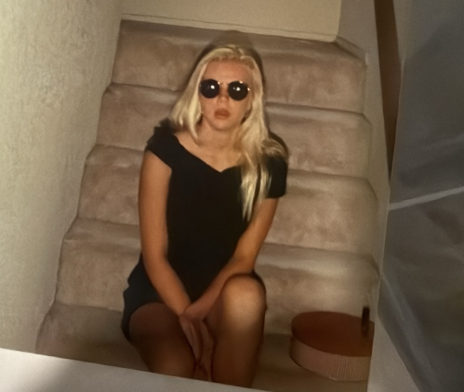Alysha in sunglasses, seated on a staircase